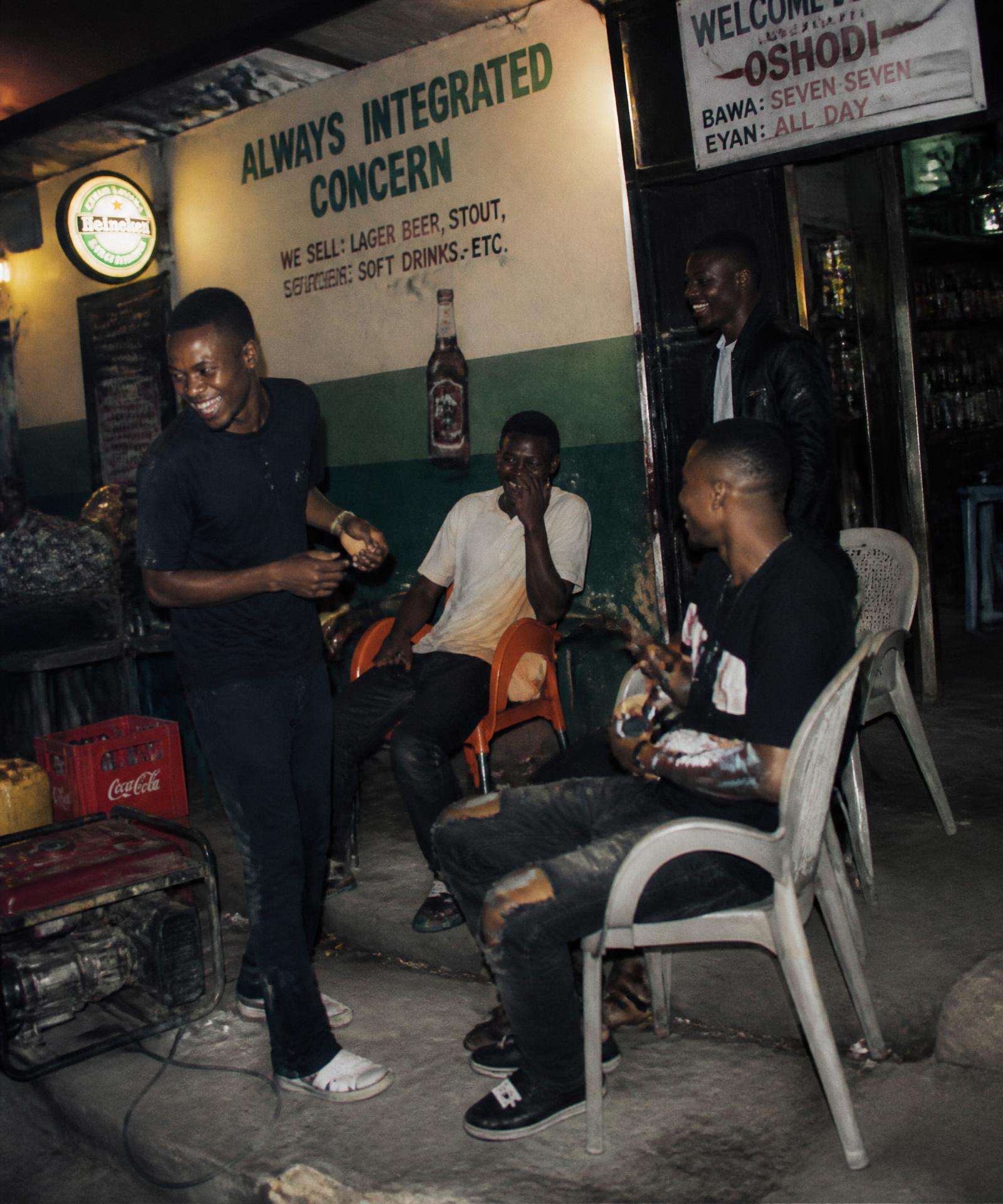 Friends laughing outside a roadside bar in Lagos at night