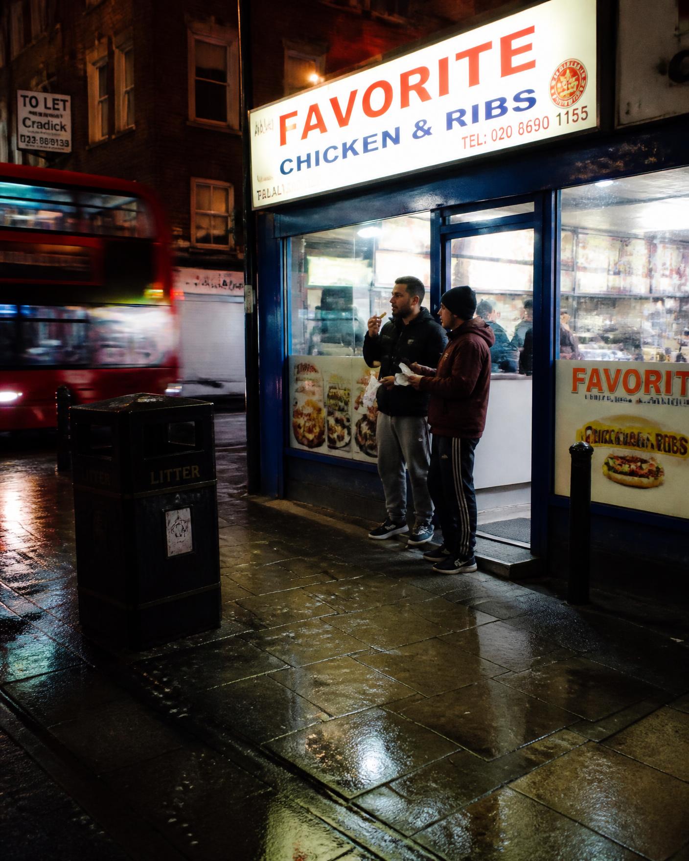 A chicken shop on a UK high street at night with neon lights